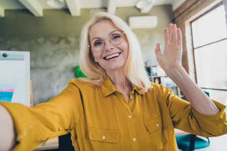 Photo of sweet charming lady assistant wear shirt video calling waving arm hi indoors workplace...