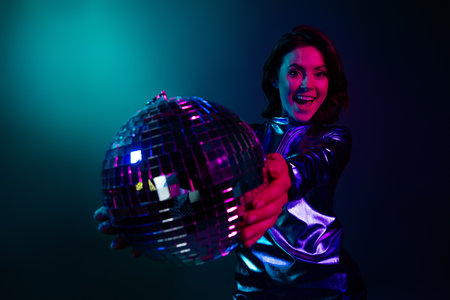 Portrait of stunning young girl excited hold glowing disco ball wear shiny dress neon light dark...
