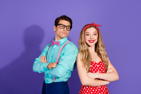 Retro styled couple posing against violet background with vibrant expressions