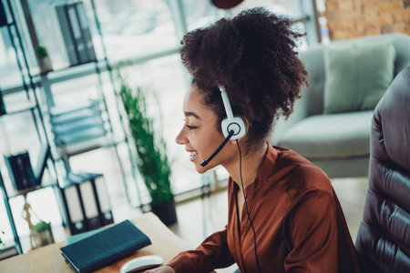Young professional woman at work in a modern office environment wearing a headset, handling business tasks enthusiasticallyの写真素材