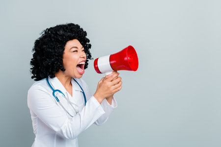 African American female doctor passionately speaking through a megaphone, showcasing medical expertiseの写真素材