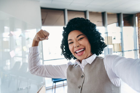 Happy young professional woman celebrating success with confidence and ambition in a modern office...