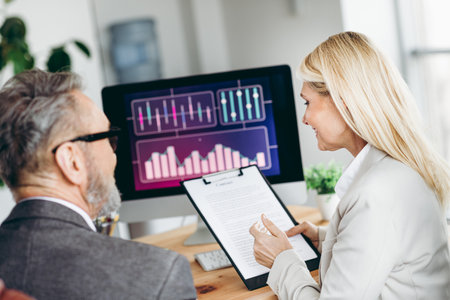 Business professionals collaborating in a modern office, analyzing data on a computer and discussing...