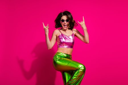 Excited young woman in vibrant outfit posing against vivid magenta background
