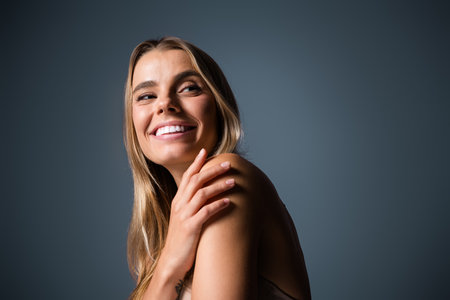 Young woman with radiant smile posing against a minimalist background, showcasing natural beauty and confidenceの写真素材