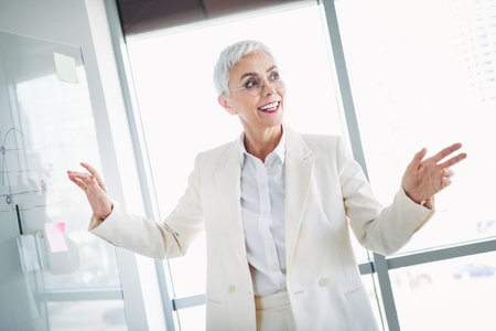Confident professional businesswoman in formal suit presenting during a dynamic office meetingの写真素材