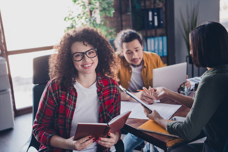 Smiling young professionals collaborating in a modern office space during a daytime meetingの写真素材