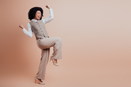 Elegant young businesswoman in stylish professional attire posing confidently against a beige backdropの写真素材