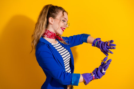 Young stylish woman posing against yellow background showing playful pose with trendy accessories