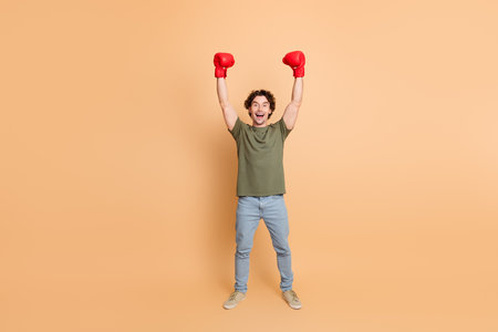 Young man wearing casual attire celebrating with raised fists and boxing gloves