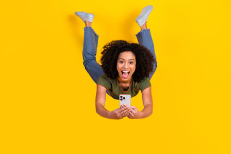 Energetic young woman taking a selfie with a joyful expression on a vibrant yellow background...