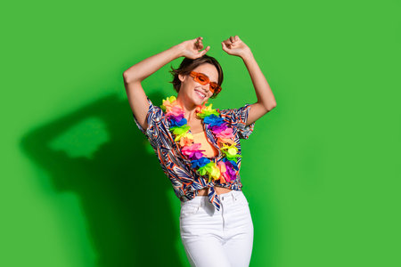 Portrait of positive girl with bob hairdo wear print shirt glasses hawaii necklace dancing hands up...