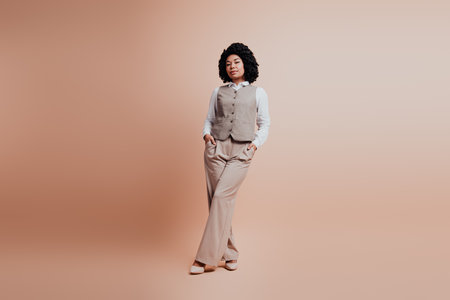 Confident businesswoman in formal beige attire posing against monochromatic background with elegant and professional demeanorの写真素材