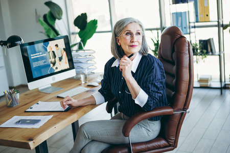 Professional senior businesswoman working in a modern office environment with confidence and elegance for her careerの写真素材