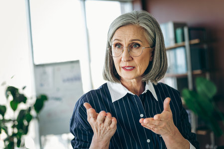 Confident mature businesswoman presenting ideas in a modern office setting, showcasing leadership...