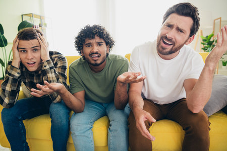 Portrait of three best friends sit couch unsatisfied football game gather chill free time modern interior flat indoorsの写真素材