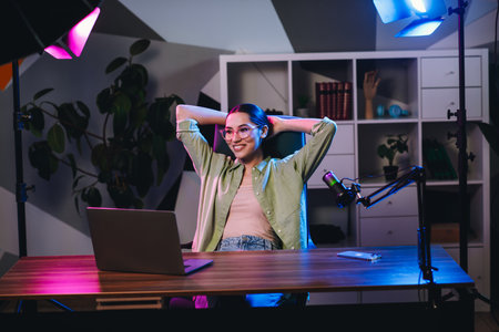 Young woman creating content at home office with colorful lighting