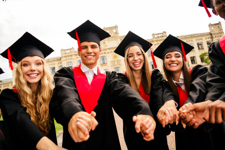 Joyful group of young graduates celebrating outdoors on a sunny day after receiving their degrees...