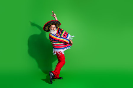 Elderly man in traditional Mexican attire posing with vibrant expressions against a green backgroundの写真素材