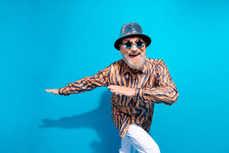 Glamorous Stylish Elderly Man Posing in Trendy Outfit With Vibrant Blue Backgroundの写真素材