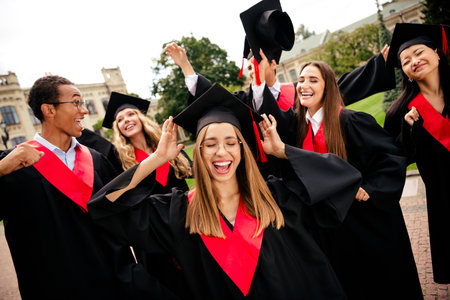Joyful graduates celebrating their success on a summer day as they receive their degrees at the university campus.の写真素材