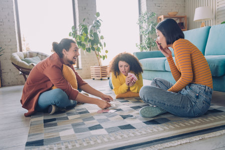 Joyful group of young diverse friends playing cards in a comfortable living room, sharing laughter and a lighthearted momentの写真素材