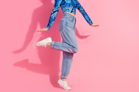 Young fashionable woman posing in casual chic denim and stylish blue top against a vivid pink...