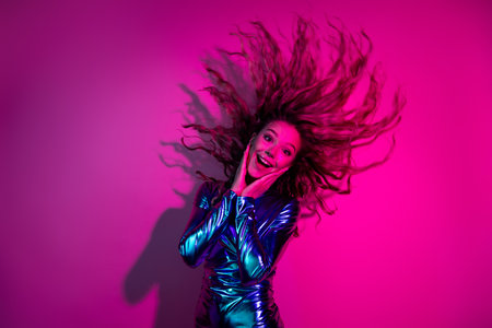 Joyful woman with flowing hair in blue dress, celebrating under neon pink light, radiating...