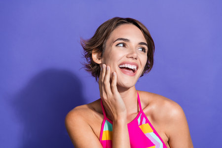 Photo of cheerful shiny hilarious woman wear trendy outfit arms touch face look up empty space isolated on purple color backgroundの写真素材