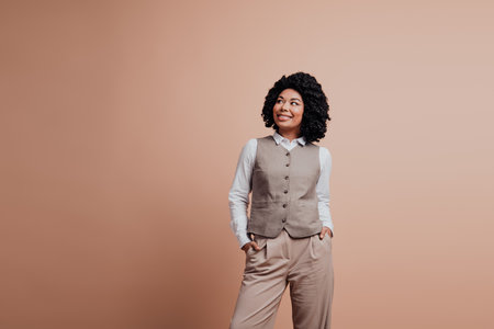Confident young businesswoman wearing elegant formal attire with a beige background, projecting a professional and poised demeanorの写真素材