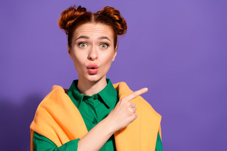 Stylish young woman with a vibrant hairstyle gesturing and expressing surprise against a purple backgroundの写真素材