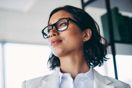 Professional businesswoman in a modern office setting confidently looking ahead towards successの写真素材