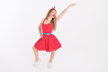 Young woman dancing in a retro polka dot dress showcasing joyful motion and stylish confidence, highlighting nostalgic glamourの写真素材