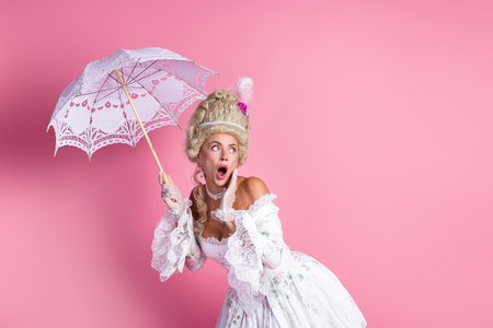 Sophisticated aristocratic woman in Baroque-era gown with lace parasol on pink backdrop, capturing...