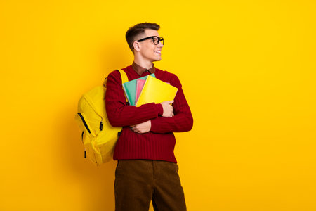 Adult Student Young Male Student Holding Notebooks Against a Vibrant Yellow Backgroundの写真素材