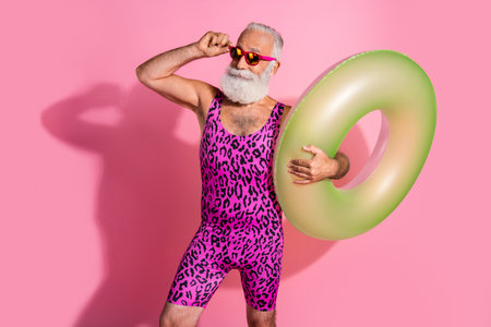 Photo of positive pensioner man wear swimwear hold lifebuoy vacation resort empty space isolated on...
