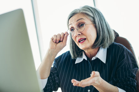Mature businesswoman discussing ideas during a video conference in her office while expressing active engagementの写真素材