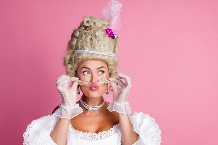 Elegant woman in historical costume showcasing humor and grace against a pink background