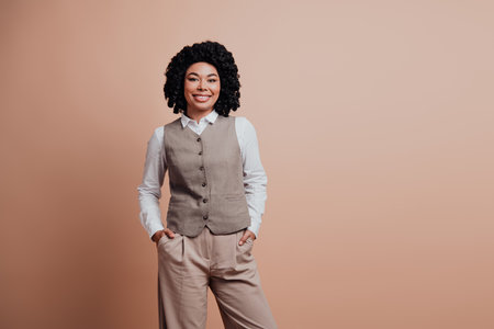Professional young businesswoman with confident smile wearing stylish formal suit against beige background in studio settingの写真素材