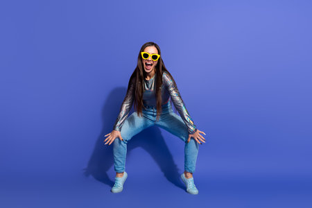 Young woman in stylish outfit posing with cheerful energy against vibrant purple background exuding...
