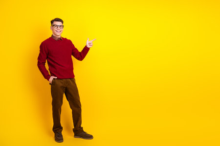 Cheerful Young Man Posing Against Yellow Background in Trendy Sweater with Confident Gestureの写真素材