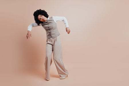 Stylish businesswoman in professional attire posing confidently against a pastel beige background