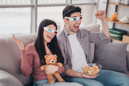 Excited Couple Bonding at Home Watching a 3D Movie with Snacks and Fun Atmosphereの写真素材