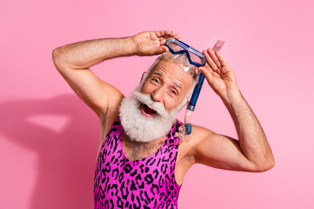 Photo of cheerful old man wear swimwear summer resort hold diving goggles isolated on pink color backgroundの写真素材