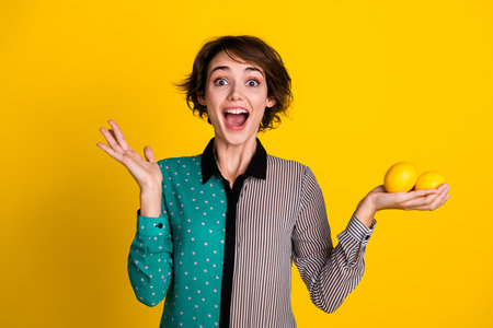Photo of positive cheerful nice woman open mouth wear stylish clothes hold lemon isolated on yellow color backgroundの写真素材