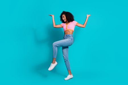 Portrait of a young woman joyfully posing in trendy outfit with teal backgroundの写真素材