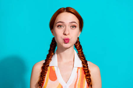 Photo of pretty young woman with pouted lips, wearing a dress, isolated on teal color backgroundの写真素材