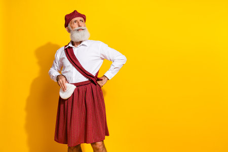 Stylish older man in traditional Scottish attire posing confidently against a vibrant yellow...