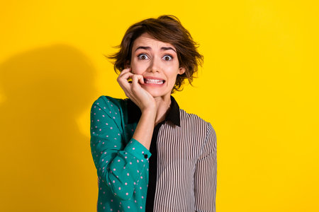 Photo of frightened girl wear stylish striped clothes isolated on yellow color backgroundの写真素材