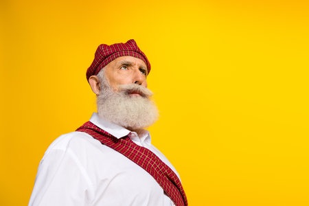 Portrait of a mature man in ethnic clothing against yellow background, depicting Scottish culture, tradition, and styleの写真素材